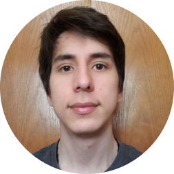 Portrait photograph of Jose Sanchez-Sossa, a young man with dark hair wearing a dark colored shirt, against a wooden background.