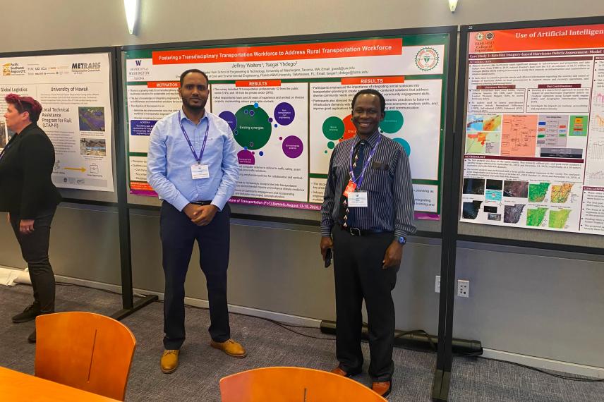 Two researchers present their research poster on transportation workforce development at an academic conference, standing in front of a detailed poster board display.