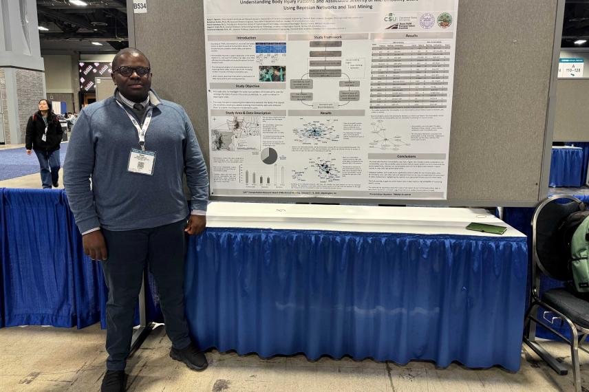 Researcher presenting at academic poster session on body injury patterns in micromobility users, standing before large research poster with data visualizations and study results.