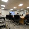 University research meeting in progress with six participants seated around a conference table, one person presenting on a wall-mounted screen.